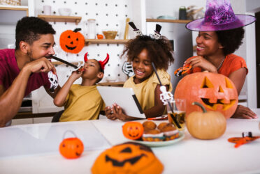 an african american family in their kitchen enjoying halloween treats with halloween decorations surrounding them