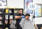 african american barber cuts the hair of a child