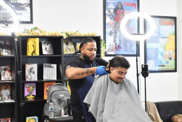 african american barber cuts the hair of a child